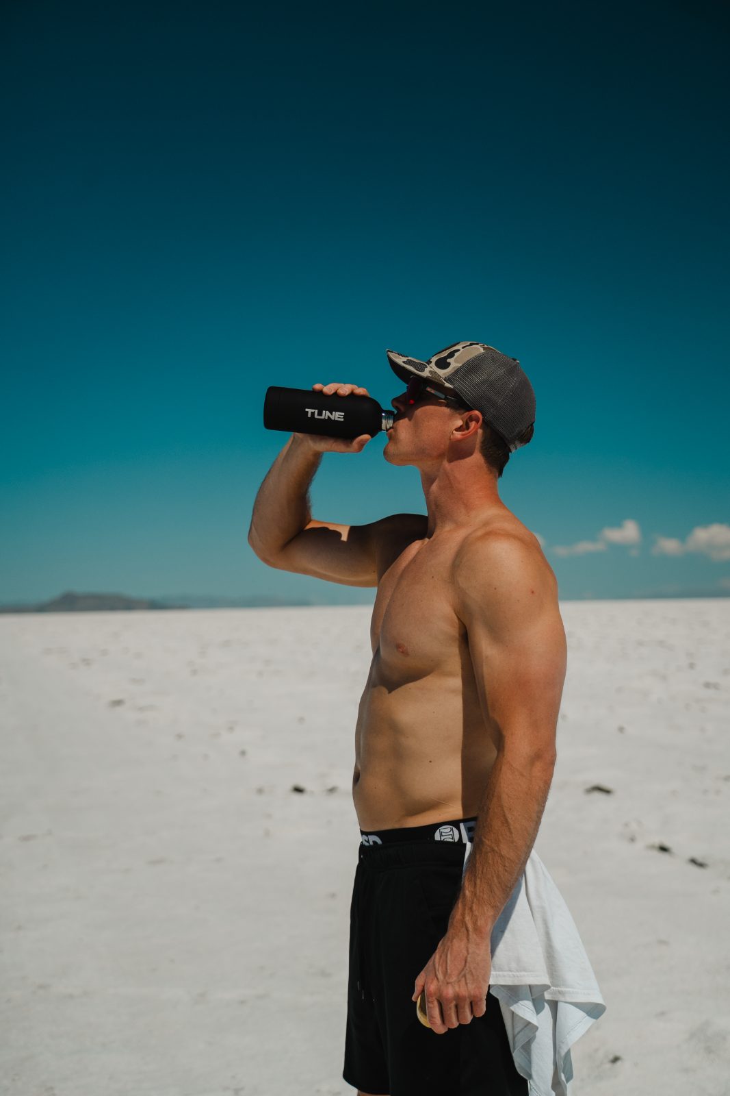 Alex drinking Tune from a bottle on the salt flats