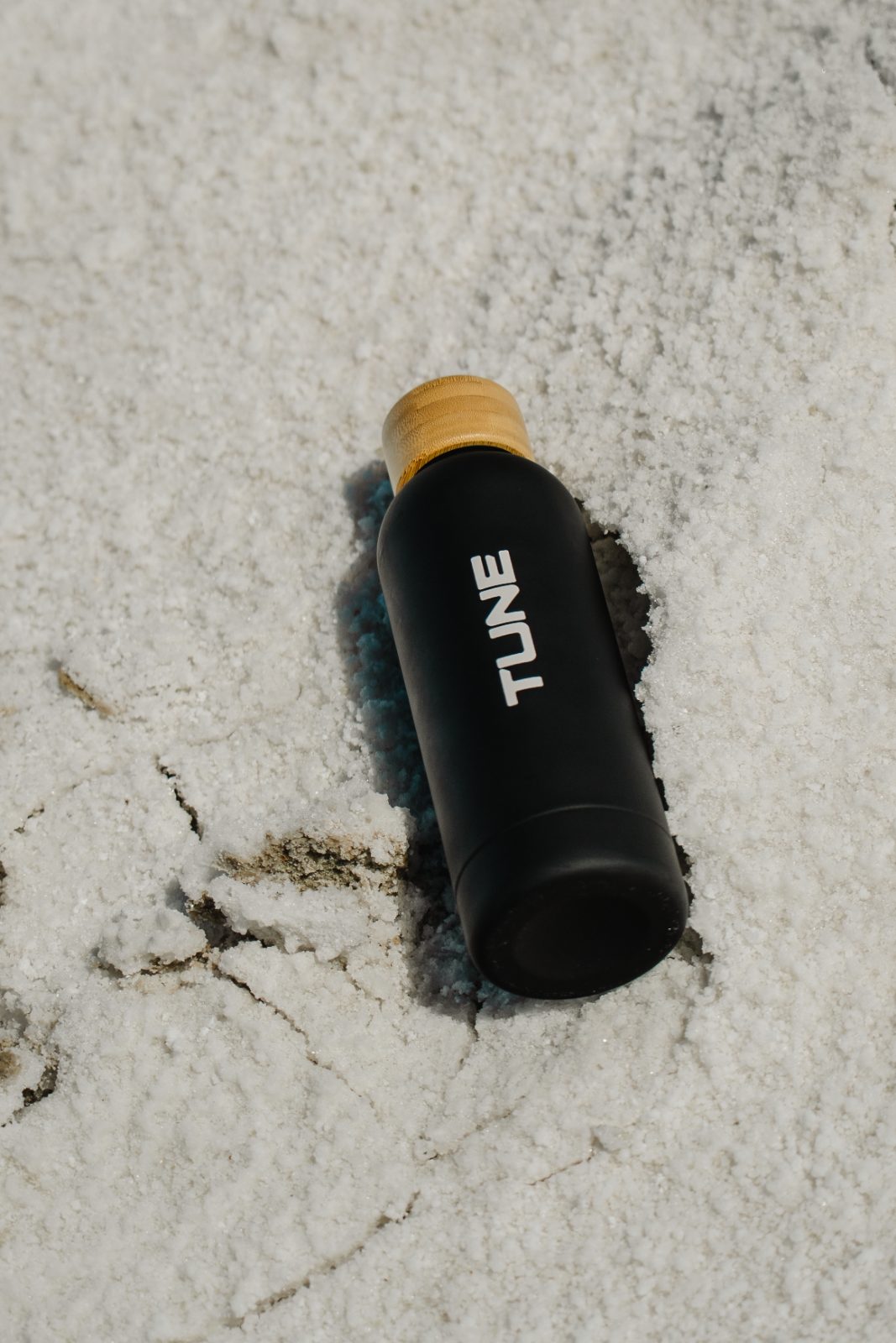 Black Tune bottle with bamboo lid lying on salt crystals