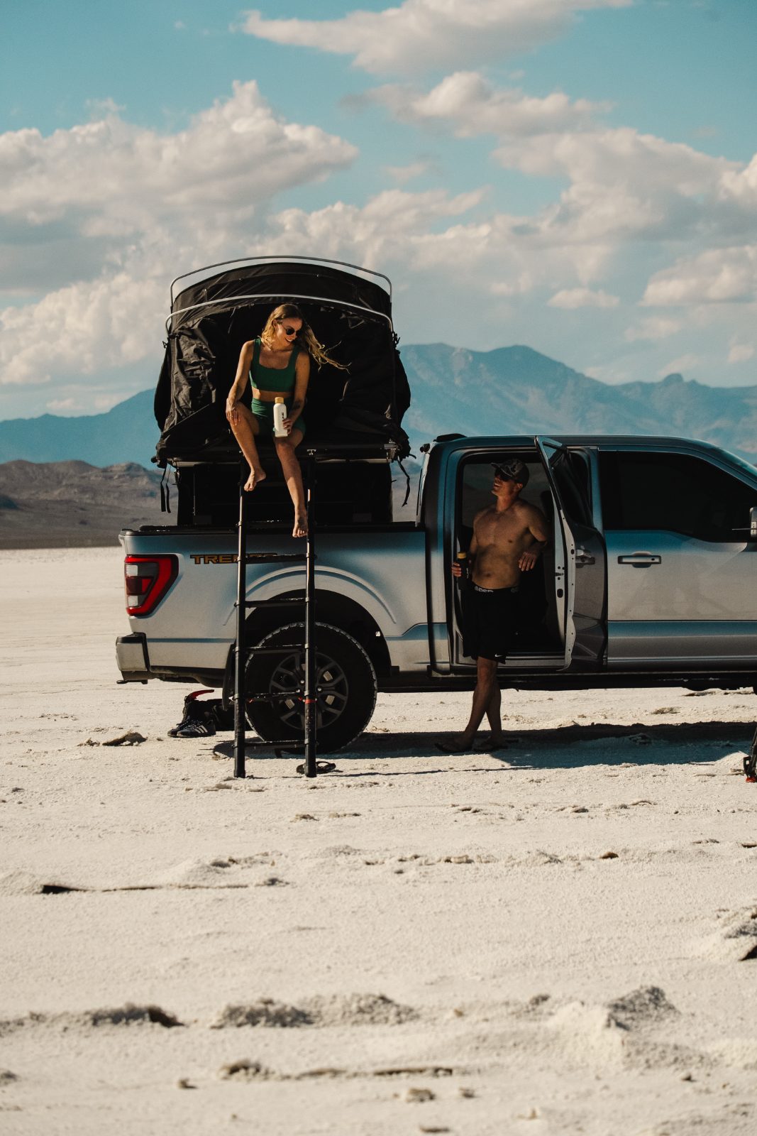 Two people at a truck camp on the salt flats with Tune bottles
