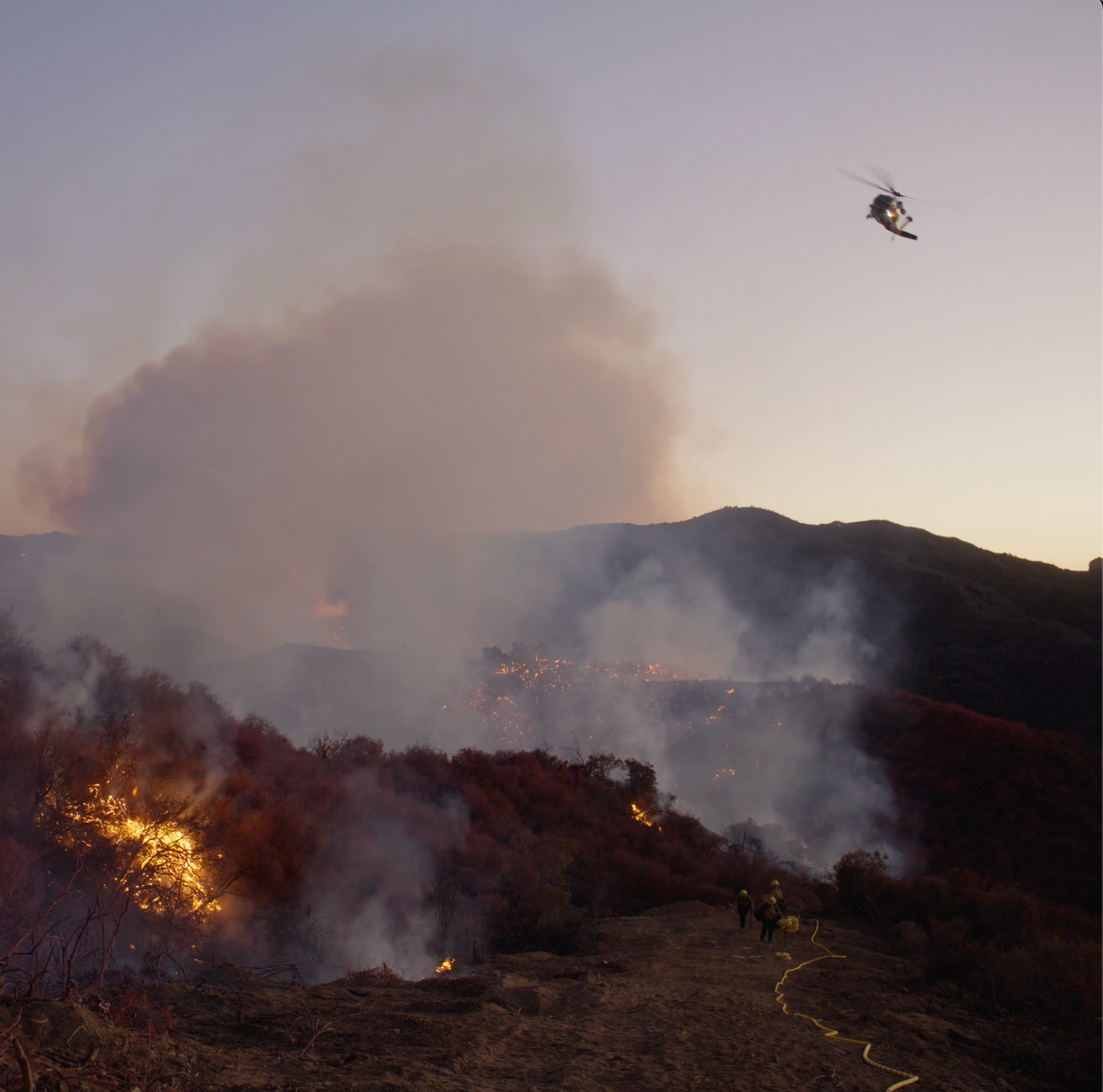 A helicopter working a wildfire at dusk