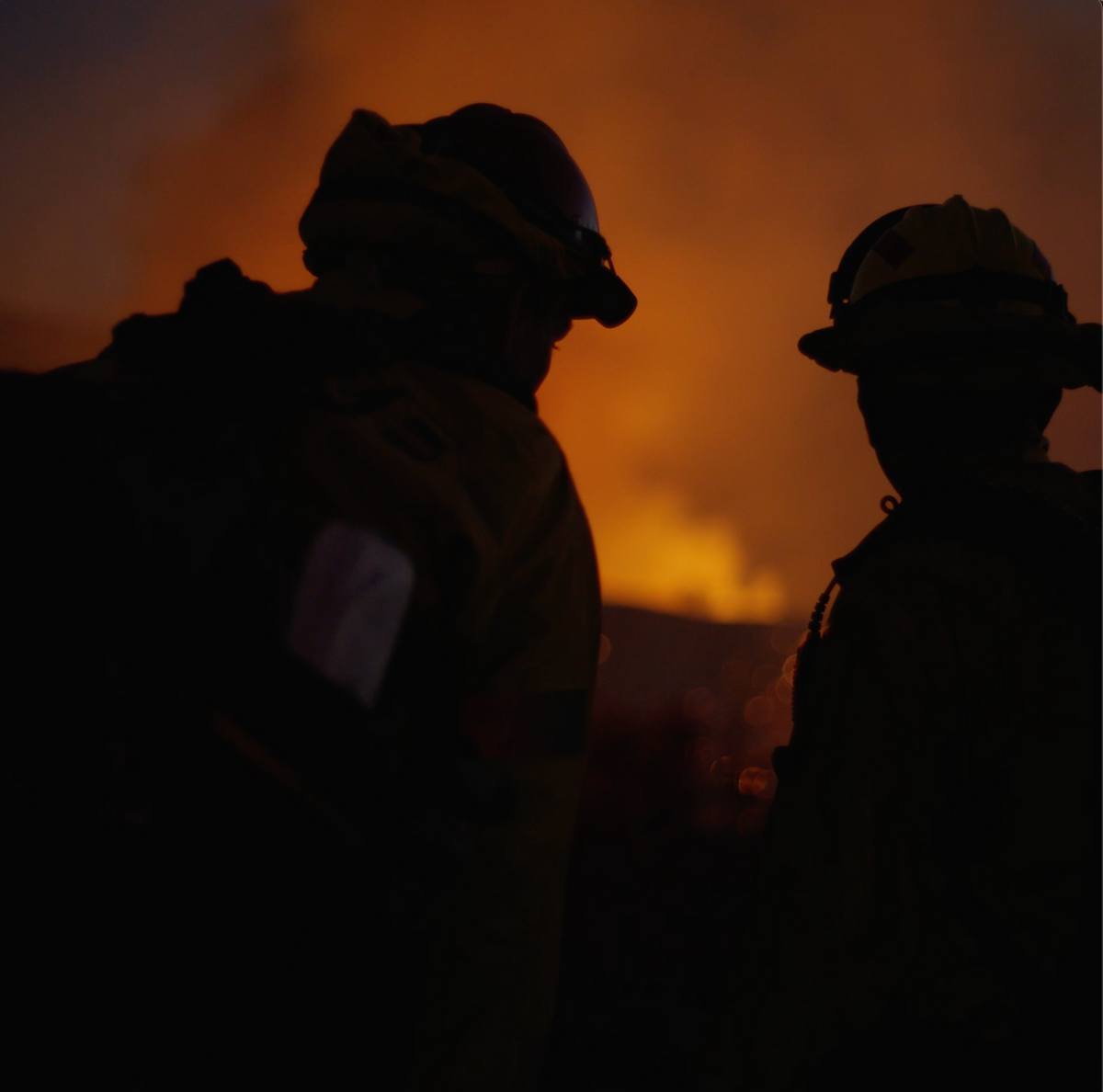 A fire crew silhouetted against a burn at dusk